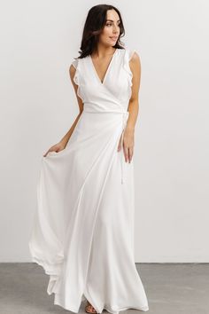 a woman is wearing a white dress with a large slit in the front and an asymmetrical neckline