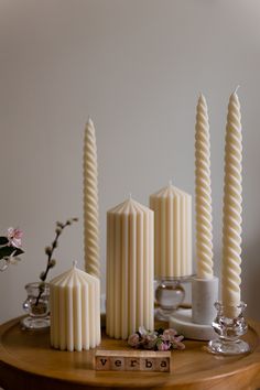 four candles sitting on top of a wooden table next to a cup and saucer