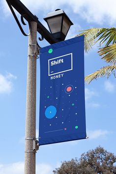 a blue sign hanging off the side of a light pole next to a palm tree