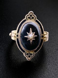 The Victorian Era was a hot time for all things celestial. When Halley's comet soared across the heavens in 1835, star themed jewelry was sought after by all the fashionable ladies and gentlemen!  Tiaras, necklaces and of course, brooches were embellished with star motifs, symbolizing a modern age, and to the sentimental Victorians, hope. The trend continued well into the Edwardian Era, with Queen Alexandra being known for wearing countless star brooches across her bodice. Introducing "Dark Angel"-a stunning addition to anyone who collects antique jewelry! Crafted in 12 karat gold, it has an onyx cabochon with a seed pearl star motif center. Accented with black enamel, it may have once been worn as a mourning ring. An altogether fabulous piece, and of course, it will pair so well with our Victorian Pearl Jewelry, Onyx And Pearl Ring, Dark Rings Aesthetic, Victorian Wedding Ring, Jewelry Mood Board, Halley's Comet, Gothic Engagement Ring, Queen Alexandra, Elven Jewelry