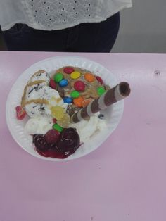 a paper plate filled with ice cream, jelly beans, and cookies on top of a pink table