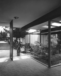 black and white photograph of the inside of a glass walled building with stairs leading up to it