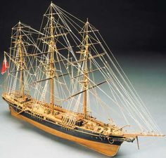 a wooden model ship with sails and two masts