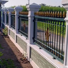 the fence is made of metal and has many bottles on it's top posts