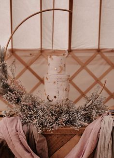 a wedding cake sitting on top of a wooden table next to a basket filled with flowers