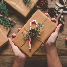 two hands holding a wrapped present with a candy cane