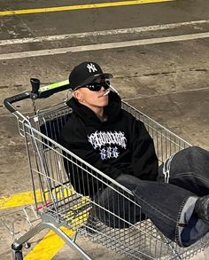 a man sitting in a shopping cart with a baseball cap and sunglasses on his head