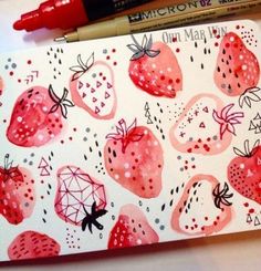 a notebook with strawberries on it next to a marker