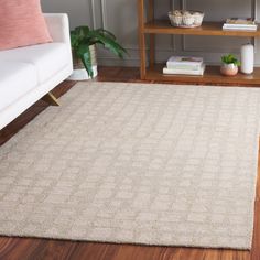 a living room area with a white couch and wooden flooring that has a beige rug on top of it