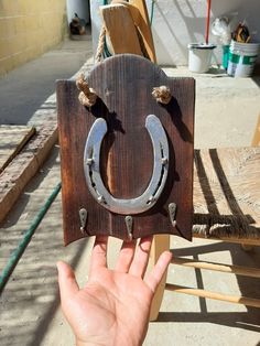 a hand is holding up a wooden horseshoe