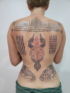 the back of a woman's body with tattoos on it