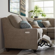 a living room with a sectional couch and chair in front of a large window on the wall