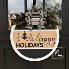 a happy holidays sign hanging on the front door with pine cones and evergreens around it