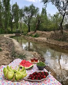 watermelon, melons and other fruits on a picnic table by the river