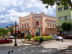 an old pink building on the corner of a street with cars parked in front of it