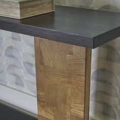 a wooden table sitting in front of a wall covered with patterned wallshadow paper