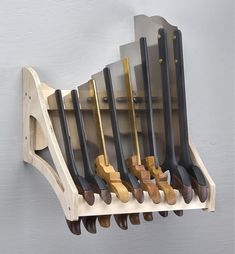 a wooden rack with many different types of knives hanging from it's sides on the wall