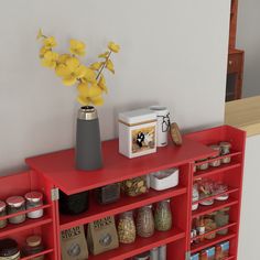 a vase with yellow flowers sitting on top of a red shelf next to other items