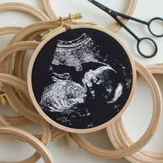 an embroidery project with some scissors and thread on the table next to it is a photo of a man's face