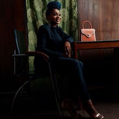 a woman sitting in a chair with a handbag on the table next to her