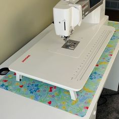 a sewing machine sitting on top of a white table next to a computer monitor and keyboard