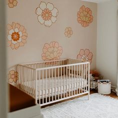 a baby's room with flowers painted on the wall and a white crib