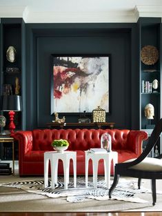 a living room filled with furniture and a painting on the wall above it's red couch