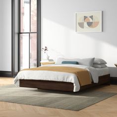 a bed sitting on top of a wooden floor next to a window