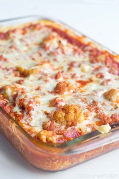 a casserole dish with meatballs and cheese in it on a white surface