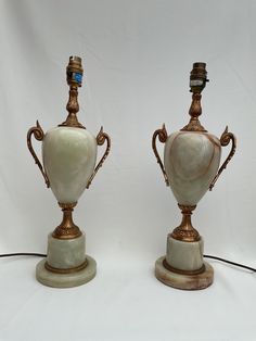 two antique vases are sitting side by side on stands, one with a blue bead in the middle