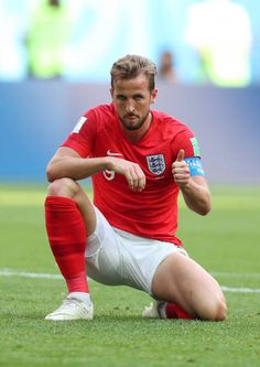 a man sitting on top of a soccer field holding a water bottle and giving the thumbs up