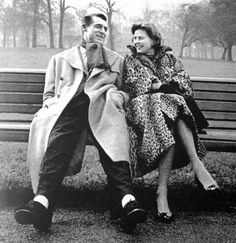 an old black and white photo of a man and woman sitting on a park bench