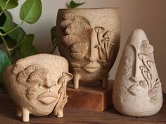 three ceramic vases sitting on top of a wooden table next to a potted plant