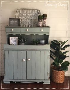 an old dresser is painted blue and has plants on top, along with other items