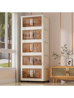 a white cabinet with glass doors and drawers in a living room next to a window