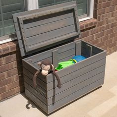 a toy box with a stuffed monkey in it on the side of a brick building