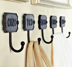 three hooks are hanging on the wall with two coats and one towel holder in front of them