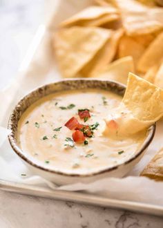 a bowl of dip with tortilla chips on the side