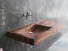 a bathroom sink made out of wood in a room with concrete walls and tile flooring