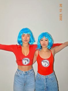 two women with bright blue hair are posing for a photo together in red tops and jeans