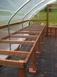 a wooden bench sitting inside of a greenhouse filled with lots of glass and metal bars