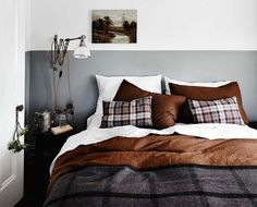 a bed with brown and white pillows in a bedroom next to a painting on the wall