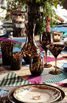 the table is set with wine glasses and vases on it's placemat