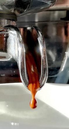 an orange sauce being poured into a silver pot