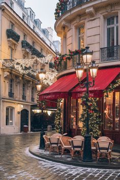 a street corner with tables and chairs covered in christmas lights