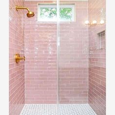 a pink tiled shower with gold fixtures and white tile flooring is shown in this bathroom