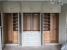 an empty room with wooden cabinets and drawers on the wall, chandelier hanging from the ceiling