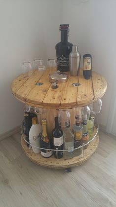 a wooden table topped with lots of bottles and glasses next to a wine glass holder