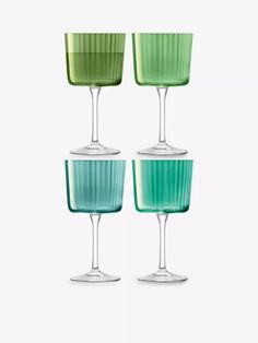 four green and blue wine glasses sitting side by side on a white surface with one empty glass in the middle