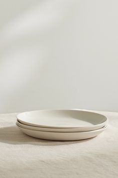 two white plates sitting on top of a table next to each other in front of a wall